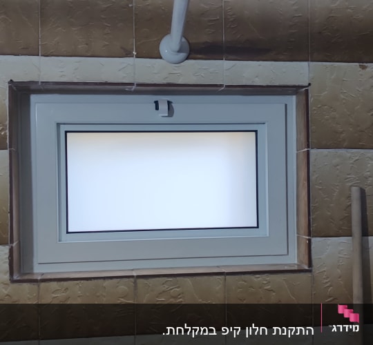 חלון אלומיניום בחדר אמבטיה עם אריחים חומים
